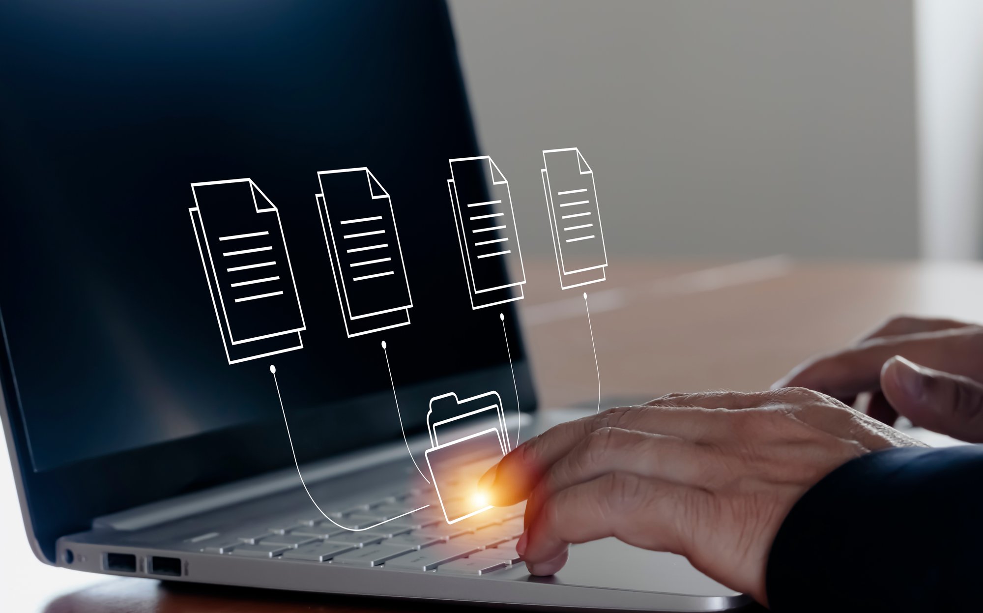 A persons' hands on a computer with graphics of a folder and documents. A persons' hands on a computer with graphics of a folder and documents.