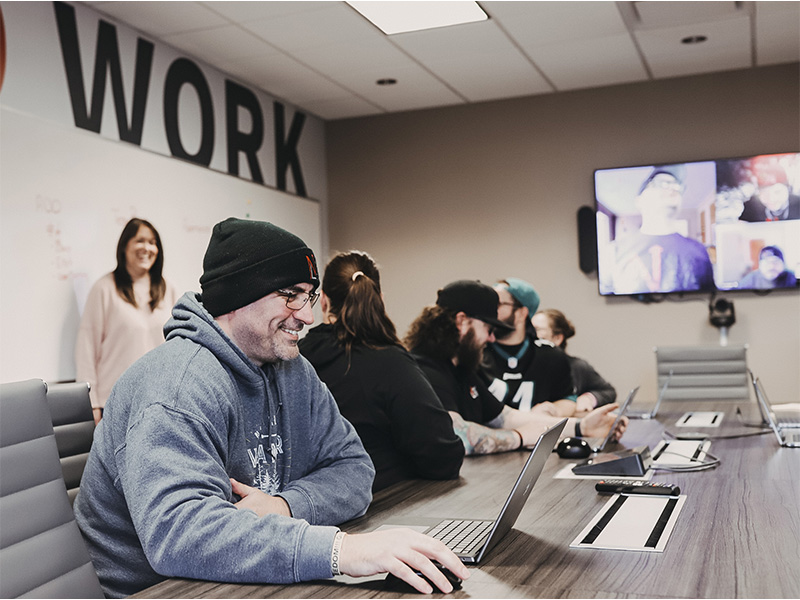 A group of people sitting at a table with laptops.